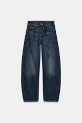 Jeans de tiro medio, color azul oscuro lavado, con corte balloon fit (holgado en muslos y estrechado en el tobillo). Presenta cinco bolsillos, cierre frontal con botones y detalle de trabilla con hebilla en la parte trasera de la cintura.
