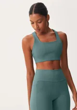 Top deportivo de escote cuadrado y espalda estilo nadador, confeccionado en tejido técnico elástico de color verde azulado.