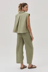 Blusa verde militar sin mangas, confeccionada en lino, con cuello camisero, cierre frontal con botones y corte holgado.