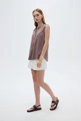 Blusa evasé de viscosa color blanco, sin mangas, con cuello a la base y escote en V con cartera frontal.