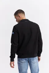 Campera de estilo deportivo con cierre frontal, confeccionada en una combinación de nylon y algodón. Presenta un diseño con paneles texturizados en las mangas, cuello alto y un parche decorativo con coordenadas en el pecho.