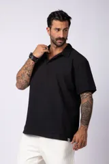 Chomba de manga corta con cuello polo, confeccionada en tejido de punto acanalado de textura pesada. Presenta un calce relajado y cuenta con una pequeña etiqueta distintiva en el ruedo.