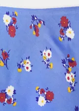 Falda corta de tiro bajo confeccionada en viscosa, con diseño estampado de flores en tonos rojos y blancos sobre base celeste, corte recto con bajo ligeramente acampanado y forro de poliéster.