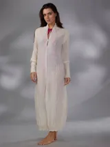 Saco largo de punto color blanco, confeccionado en 100% lana merino natural, con diseño jacquard de ramas, cuello alto, cierre frontal con pequeños botones y aberturas laterales.
