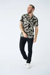 Camisa de manga corta con estampado botánico de hojas en tonos azul y blanco. Presenta cuello clásico, cierre frontal abotonado y corte slim.