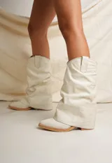 Botas texanas de cuero color crudo, con caña alta arrugada y punta fina.