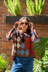 Sweater tejido de algodón con diseño de rombos multicolor en tonos marrones, azul y rojo. Presenta una silueta oversize, cuello redondo y mangas largas abullonadas con puños ajustados.
