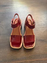 Sandalias de cuero color cereza, con tira ancha sobre los dedos, tira con hebilla al tobillo y taco cuadrado de madera.