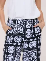 Pantalón crop ancho en color negro con estampado floral en contraste, bolsillos laterales y detalle de encaje en el ruedo.