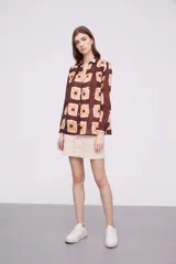 Camisa marrón con estampado de cuadrados color naranja y blanco, de corte holgado y manga larga.