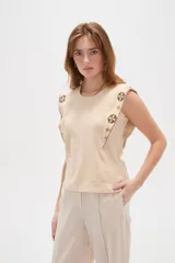 Remera negra de algodón con cuello redondo, corte al cuerpo y detalles de bordado geométrico multicolor en los hombros y sisas.