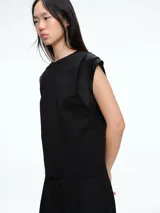 Top sin mangas de corte recto y silueta ligera, con detalle de tejido satinado en los hombros. Presenta cuello redondo y diseño minimalista.