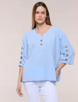 Blusa de algodón color celeste, con escote en V y botones frontales. Cuenta con mangas cortas decoradas con hileras de botones en los laterales.