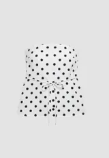 Top strapless con estampado de lunares negros sobre fondo blanco, corte en A y lazo ajustable en la cintura. Cuenta con elástico en la espalda para un mejor ajuste.