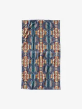 Toalla extragrande de felpa suave, con un lado de acabado aterciopelado y un diseño de bucles que garantiza una absorción superior. Presenta un estampado geométrico de estilo nativo americano en tonos azul grisáceo, naranja quemado, beige y turquesa.