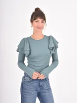 Remera de manga larga en color beige, confeccionada en tejido acanalado, con cuello redondo y detalle de volados en los hombros.