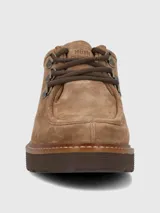 Zapato bajo de mujer color camel, estilo mocasín o derby, confeccionado en gamuza. Presenta suela gruesa de plataforma color marrón oscuro con costura visible en color claro. El sistema de ajuste es mediante cordones marrones que pasan por ojales metálicos tipo gancho.