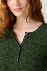 Remera de manga larga verde oscuro con estampado floral en negro, cuello redondo y botones frontales.