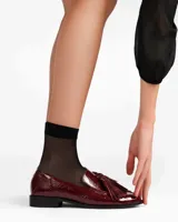 Mocasín de cuero color merlot (vino tinto) con acabado charol y borlas decorativas en el empeine.