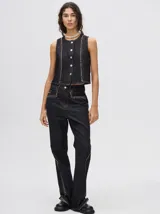 Pantalón de jean tiro alto con corte ochentoso y terminación oxford. Presenta apliques metálicos decorativos alrededor de los bolsillos delanteros y traseros, y a lo largo de la parte externa de las piernas.