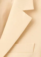 Blazer color beige confeccionado en mezcla de lino, viscosa y lyocell, de corte holgado con solapas de muesca, bolsillos con solapa en los laterales y cierre frontal de un botón.