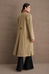Tapado de paño de lana color verde oliva, con corte regular, cuello alto y cierre frontal cruzado con botones. Presenta tajos laterales y detalles de apliques en cuero en los bolsillos y el cuello.