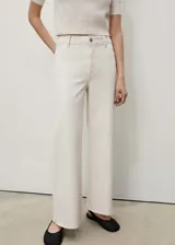 Jeans de tiro alto, corte culotte y pernera recta con bajo deshilachado. Confeccionados en tejido elástico de algodón estilo denim, cuentan con cierre de cremallera y botón, trabillas para cinturón y bolsillos traseros.