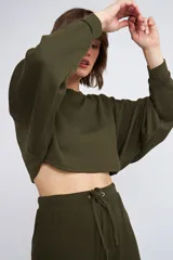 Buzo corto de tejido rib en color verde militar, con mangas largas y cuello redondo. Presenta un diseño holgado y cropped.