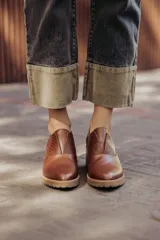 Zapato de cuero color beige, con taco de madera y suela dentada. Presenta un diseño slip-on con detalles de textura en relieve en los laterales y el empeine.