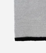 Bufanda larga gris de punto afelpado con terminaciones en negro.