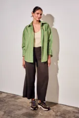 Camisa de corte oversize con estampado de rayas verticales en tonos verde, blanco y ocre. Presenta cuello clásico, cierre frontal con botones, bolsillo en el pecho y mangas largas con puños abotonados.