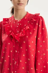 Camisa roja con estampado floral, cuello con volados y mangas largas abullonadas.