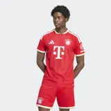 Camiseta de fútbol Adidas del FC Bayern, modelo local, color rojo con rayas verticales sutiles, detalles en blanco y dorado en el cuello y las mangas, y el logo del patrocinador en el pecho.