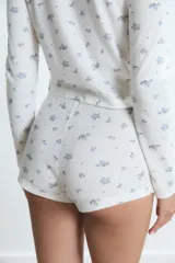 Pijama de dos piezas compuesto por una remera de manga larga con botones frontales y un short de tiro alto, ambos confeccionados en tejido acanalado con estampado floral pequeño.