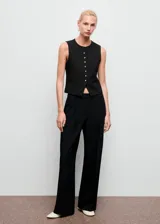 Pantalón de vestir negro de corte wide leg, con tiro medio, detalle de pinzas frontales y cierre con botón, gancho y cremallera.