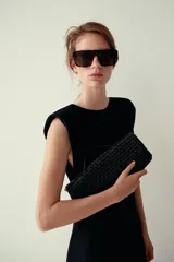 Bolso tipo sobre con diseño trenzado, asa de mano superior y cierre de solapa con imán.