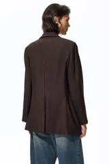 Blazer de botonadura sencilla color marrón oscuro con solapas de muesca, cierre de un botón, hombreras y bolsillos delanteros ribeteados.