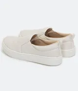 Championes slip-on color beige, sin cordones, con diseño capitoné en la parte frontal y suela blanca de goma.