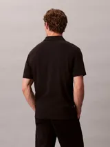 Chomba de manga corta Calvin Klein confeccionada en algodón interlock, con cuello clásico y cierre frontal de dos botones.