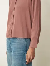 Camisa de manga larga con cuello clásico y cierre frontal de botones, confeccionada en tela con acabado satinado.