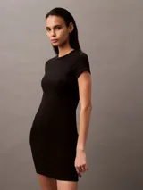 Vestido corto negro ajustado al cuerpo, de manga corta y cuello redondo. Presenta un pequeño logo bordado en el frente.