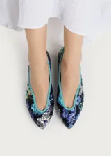 Bailarina de punta redonda con exterior cubierto de lentejuelas que forman un diseño floral multicolor sobre base azul marino. Presenta un ribete en color turquesa y suela plana de cuero.