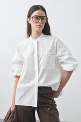 Camisa de manga larga con cuello mao, silueta relajada y sisa corrida. Presenta un bolsillo frontal aplicado y cierre frontal oculto.