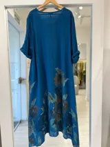 Vestido midi azul petróleo con estampado floral pintado, escote en V y mangas cortas con vuelta.