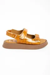 Sandalias de cuero color caramelo con textura efecto cocodrilo, suela chunky marrón y tiras ajustables con velcro.