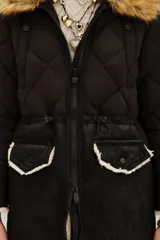 Campera negra de diseño híbrido con cuerpo acolchado en forma de rombos y mangas de textura lisa. Presenta un cuello de piel sintética desmontable en tono marrón y detalles de corderito en los puños y el ruedo. Incluye cierre frontal y cordones ajustables en la cintura.
