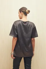 Remera negra de textura acanalada con acabado brillante, de corte holgado y mangas cortas.