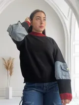 Sweater negro de punto con cuello y puños acanalados en color rojo. Mangas largas con detalle de denim.