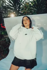 Hoodie blanco de corte oversize con capucha y diseño estampado en la espalda con letras negras.