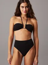 Corpiño de bikini bandeau negro con tirantes finos y detalle metálico en el centro.